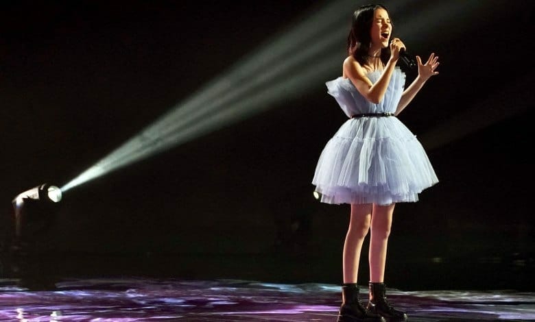 A girl singing into a microphone with passion and charisma.