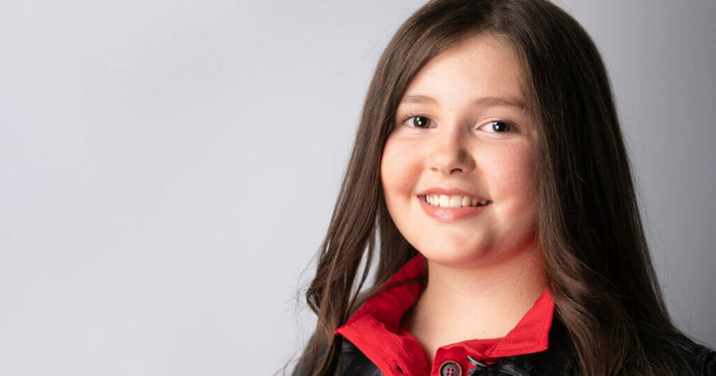 A young girl wearing a red and black jacket.