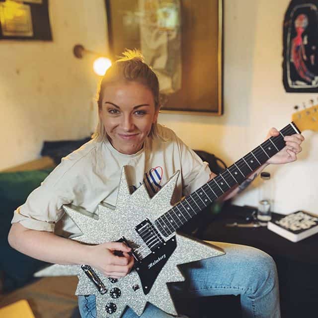 A woman playing guitar in a cozy living room.