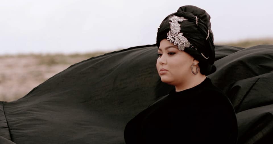 A woman wearing a turban standing in a field.