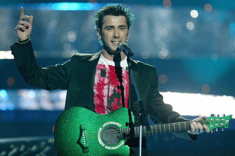 A man performing with a guitar and microphone.