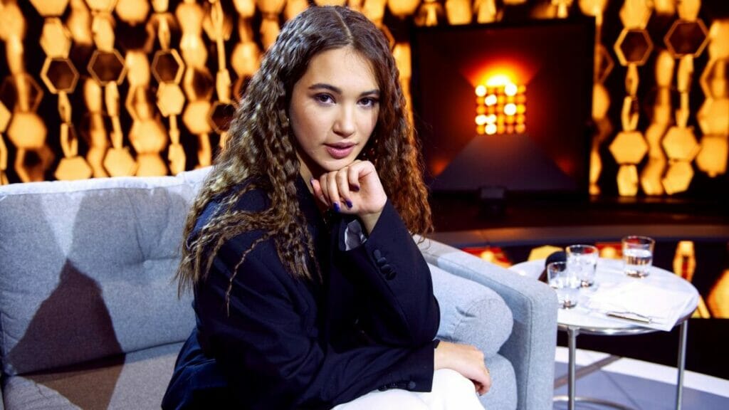A woman sitting on a couch in front of a cozy fireplace.