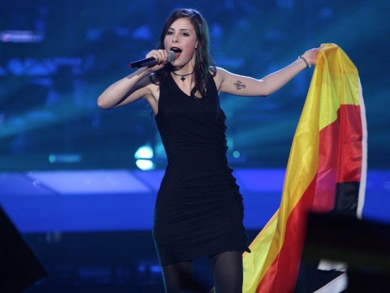 A stylish woman in a stunning black dress proudly holding a flag.