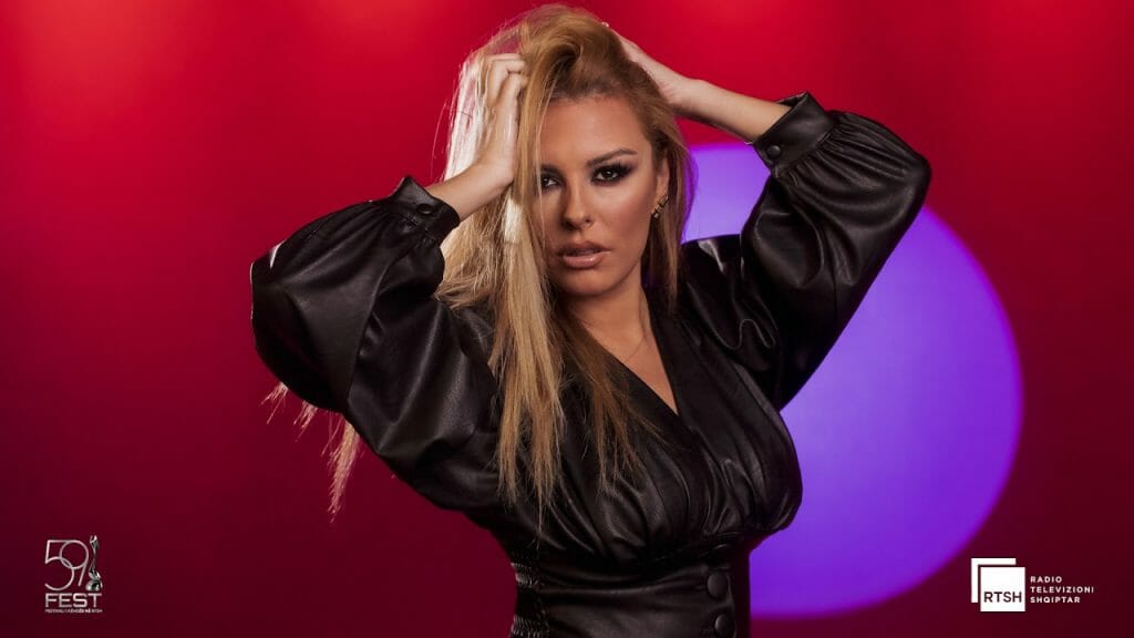 A woman in a black dress posing in front of a red light.